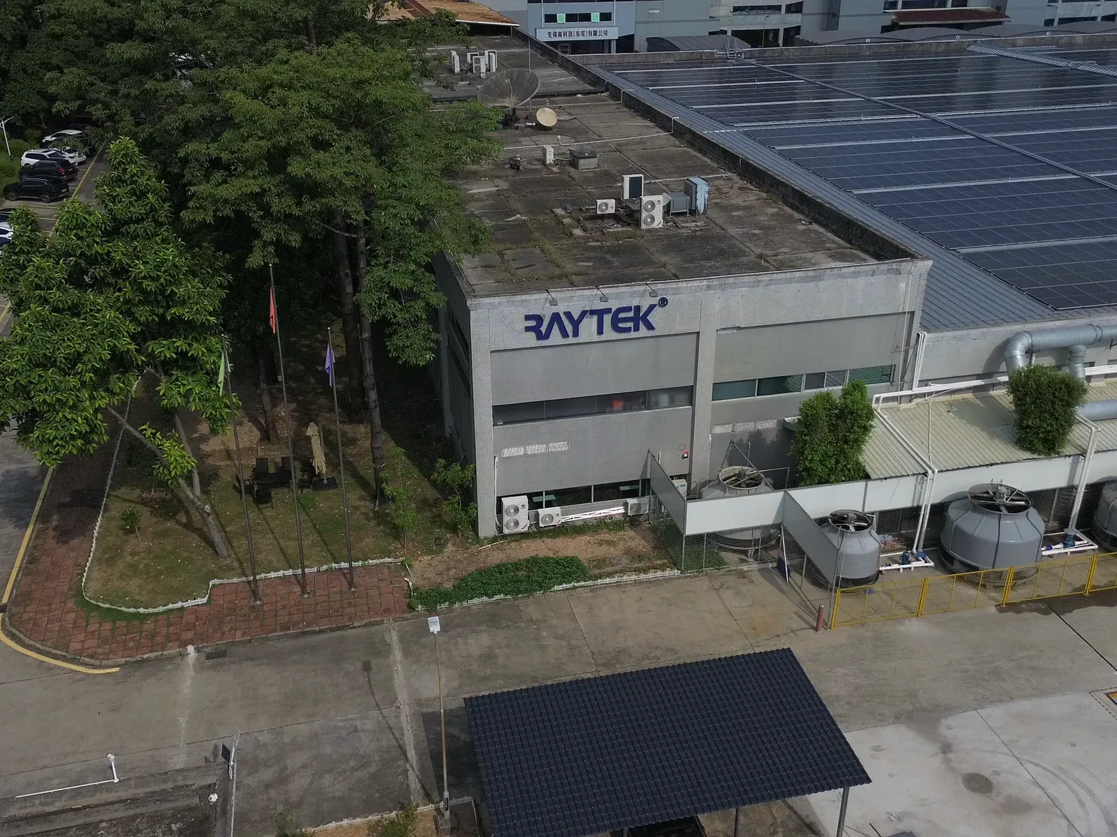 Close aerial view of the Raytek factory sign and rooftop solar installation